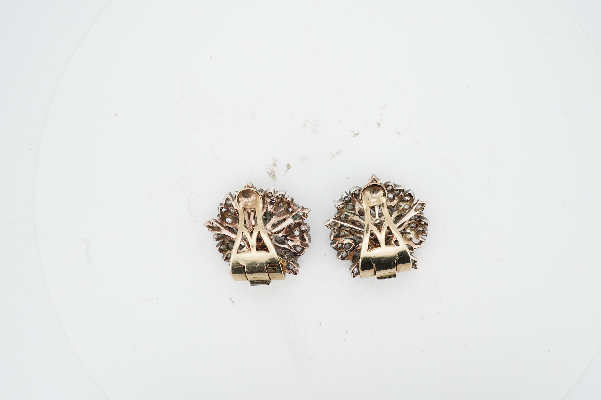 A pair of diamond ear clips 19th century and later, each designed as a wild rose, set with cushion-shaped and rose-cut diamonds, mounted in silver and gold, length 2.2cm each, later clip fittings